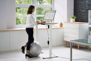 woman standing at desk with exercise ball