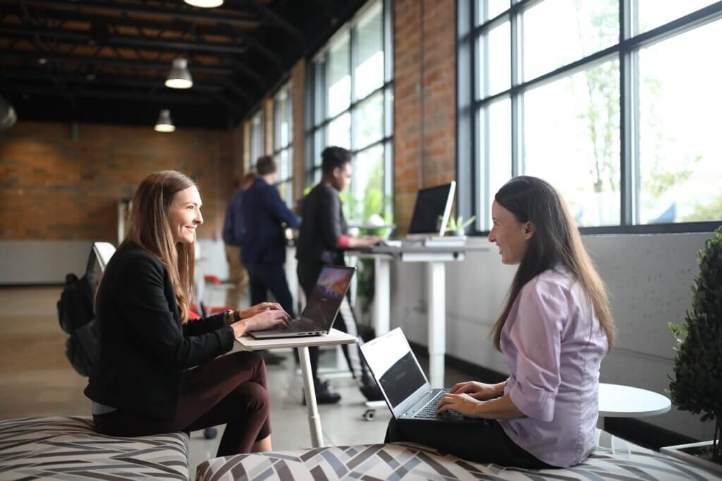 Two women working on laptops in a modern coworking space