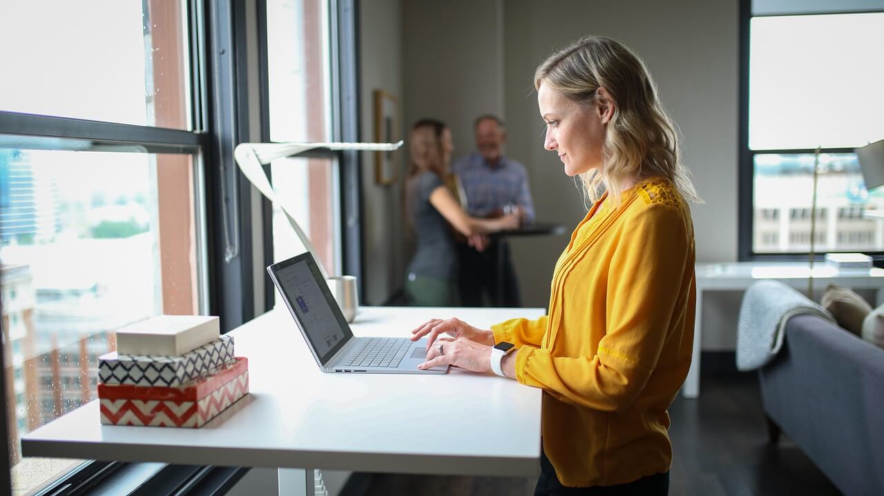 Woman working at standing desk with laptop in modern office